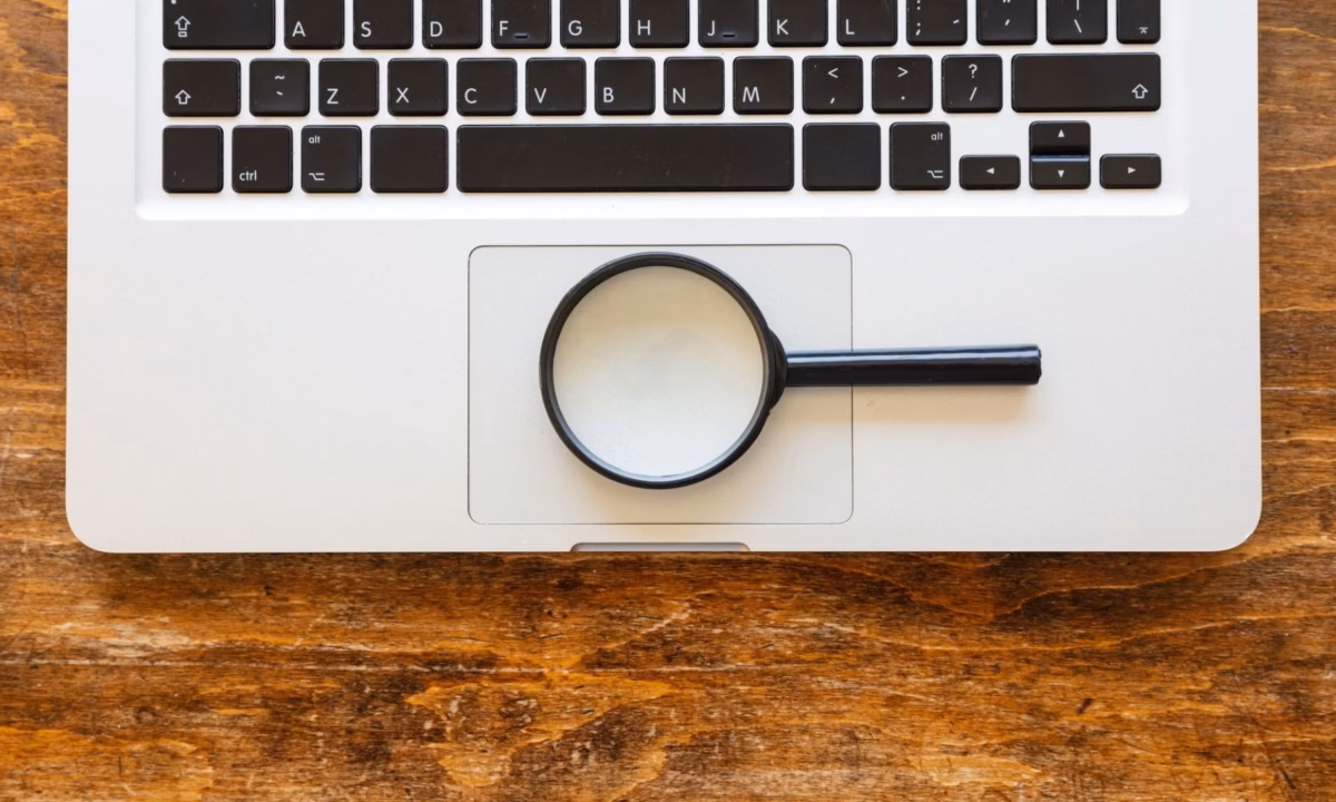 A magnifying glass perched atop a Macbook demonstrates a direct search link.