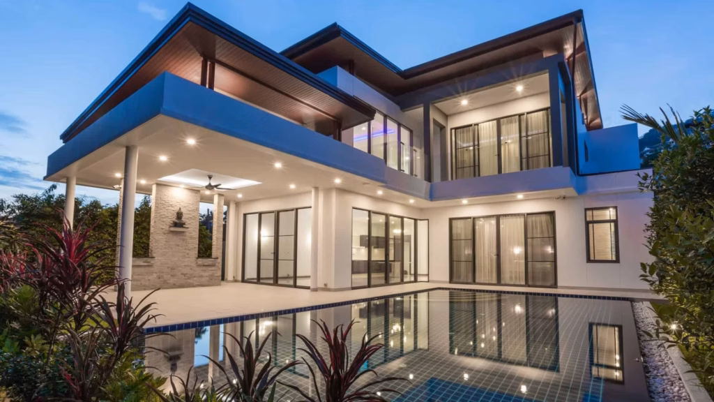 The outside of a luxurious, modern, and contemporary piece of real estate with a large pool and a night sky.