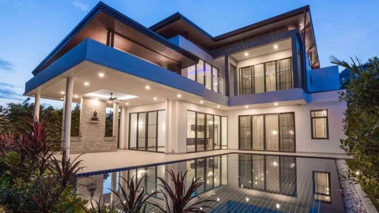 The outside of a luxurious, modern, and contemporary piece of real estate with a large pool and a night sky.