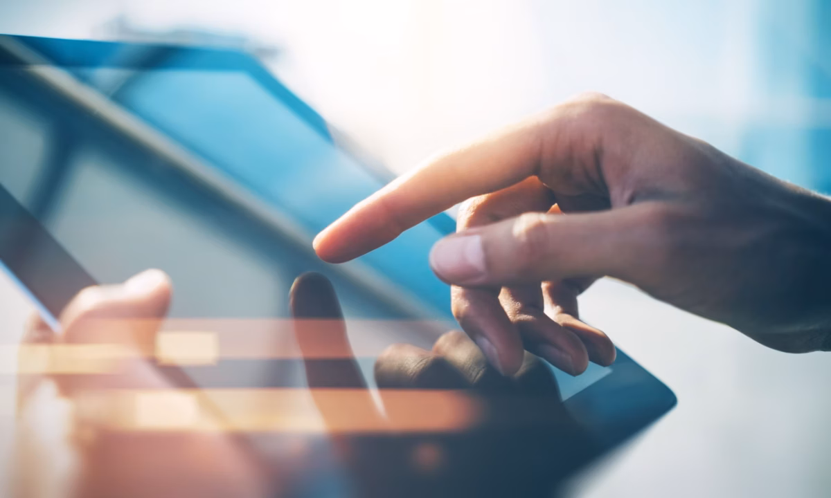 A hand touches the surface of a tablet, representing a realtor working on their digital marketing lead generation techniques
