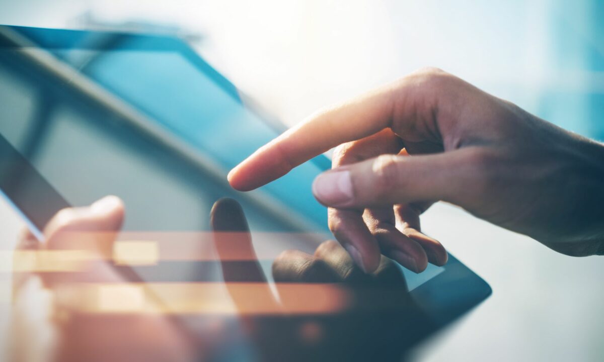 A hand touches the surface of a tablet, representing a realtor working on their digital marketing lead generation techniques