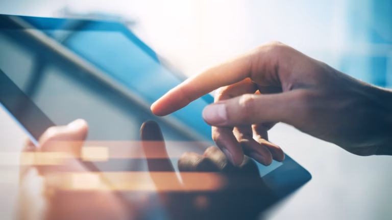A hand touches the surface of a tablet, representing a realtor working on their digital marketing lead generation techniques