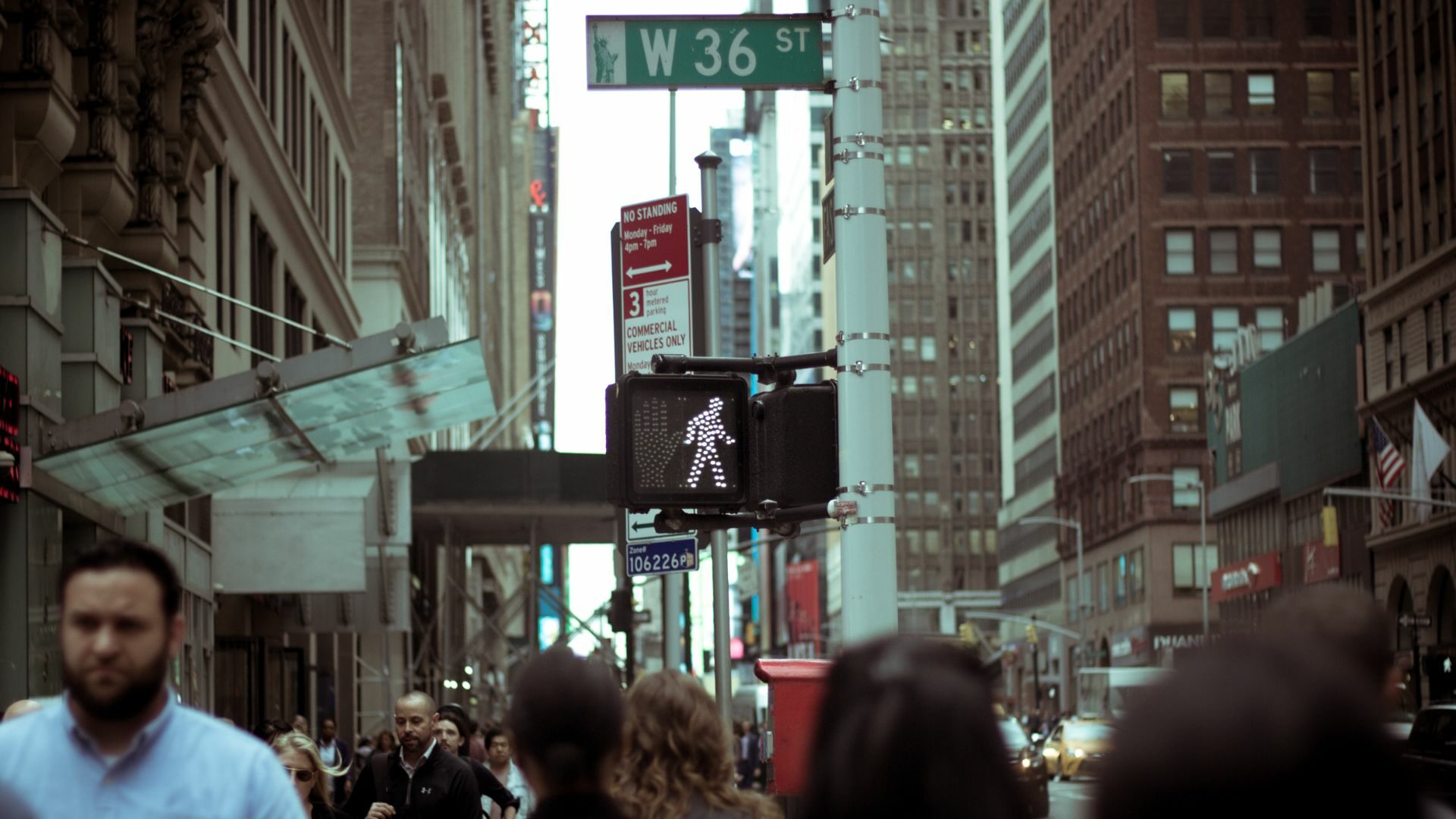 In W 36 Street, a traffic sign displays the go signal for walking pedestrians.