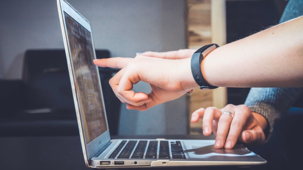 Two agents work together on a laptop discussing potential real estate blog ideas that may generate leads and improve their marketing ROI