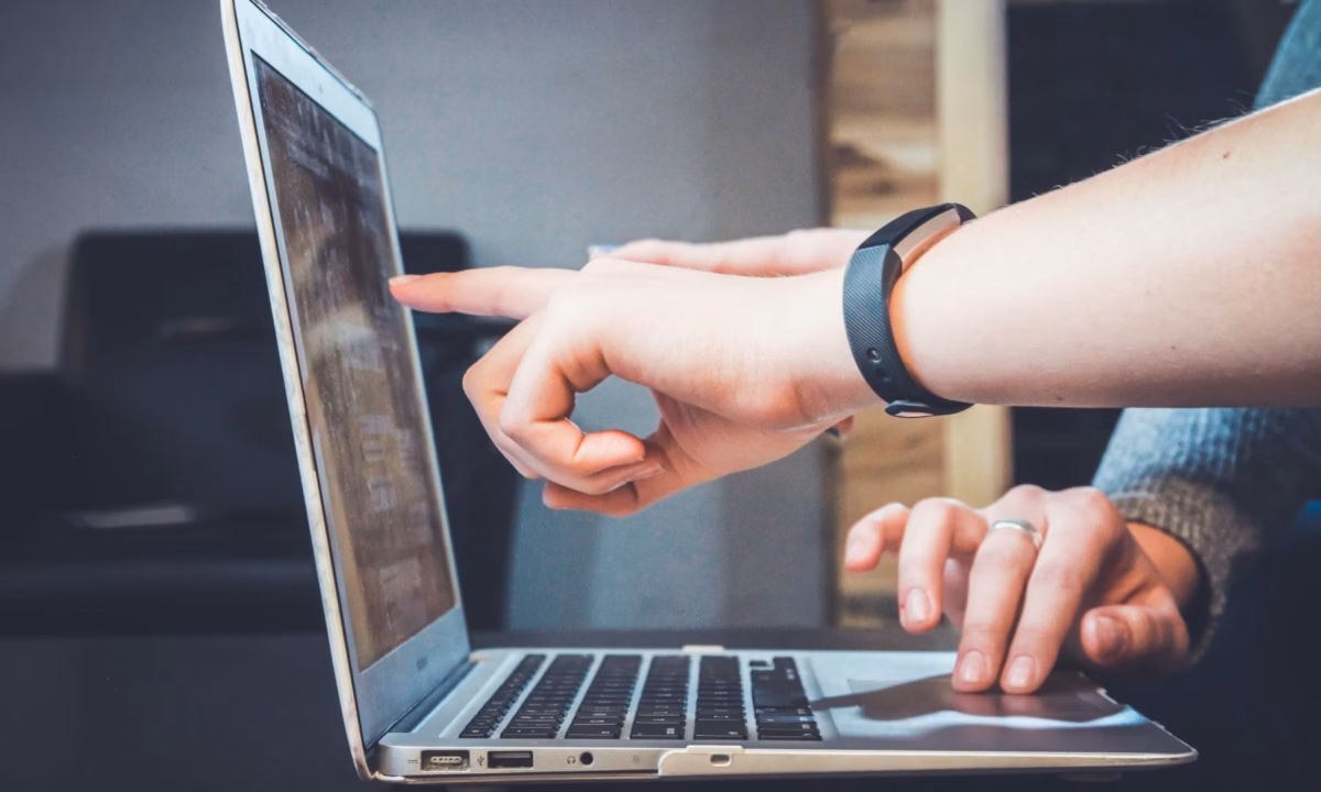 Two agents work together on a laptop discussing potential real estate blog ideas that may generate leads and improve their marketing ROI
