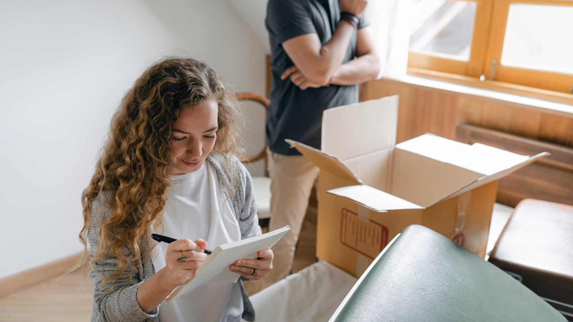 A homeowner packing up boxes consults a sellers guide for real estate created by her listing agent