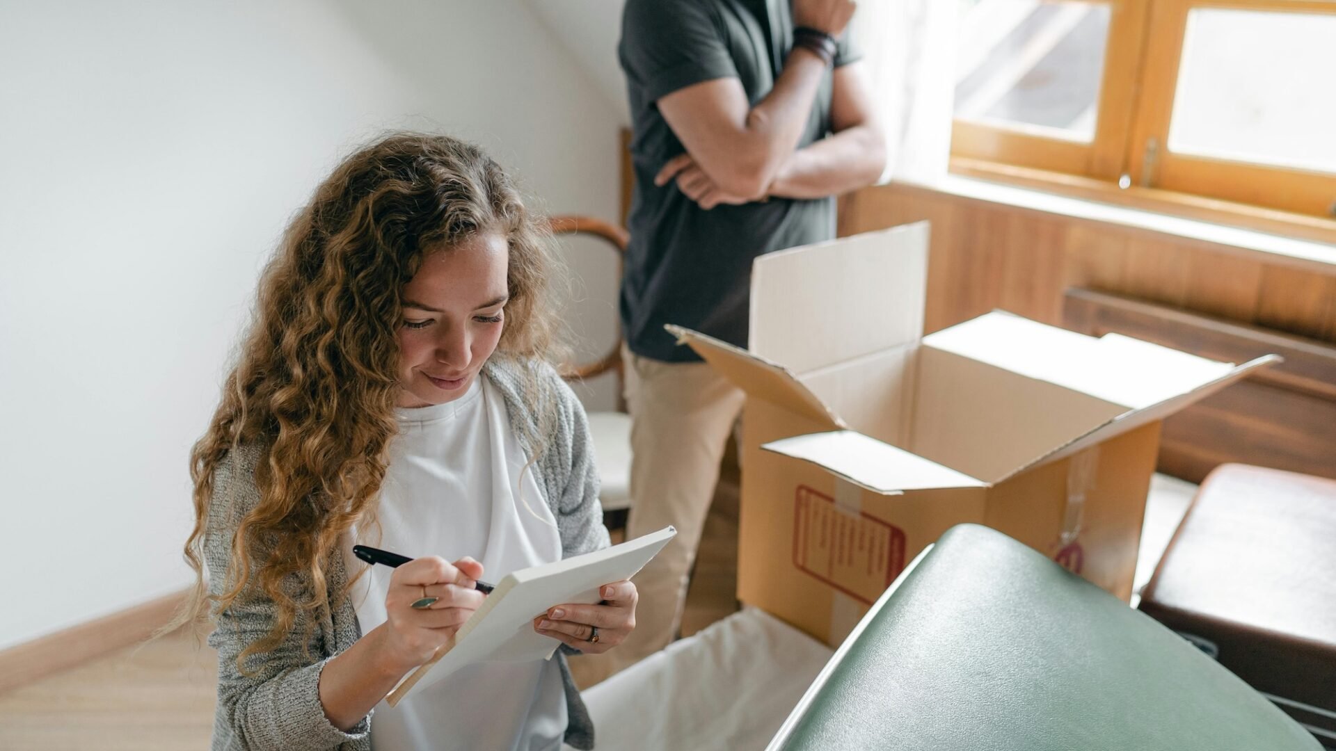 A homeowner packing up boxes consults a sellers guide for real estate created by her listing agent