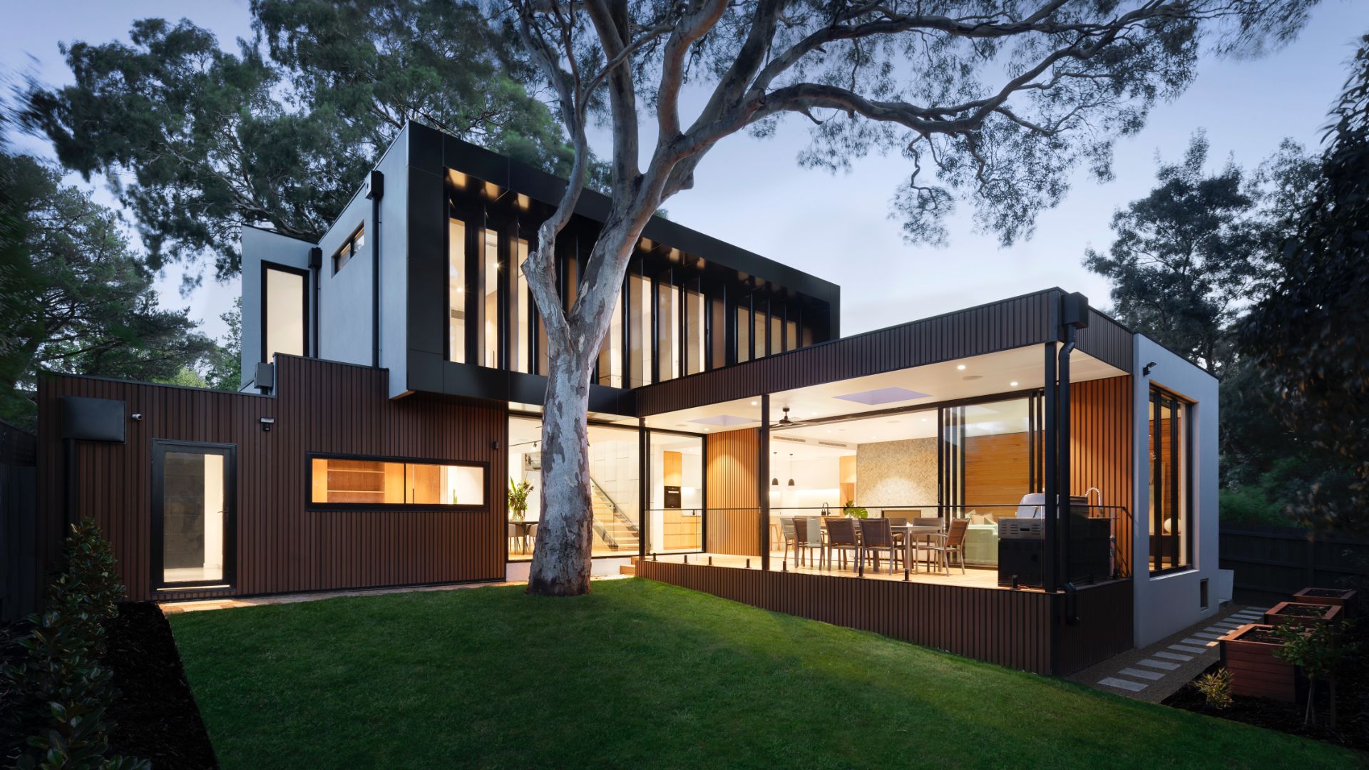 A luxurious, modern, contemporary real estate property exterior with a tall tree in front at daybreak. Used as a decorative image for a blog on how to host a virtual open house