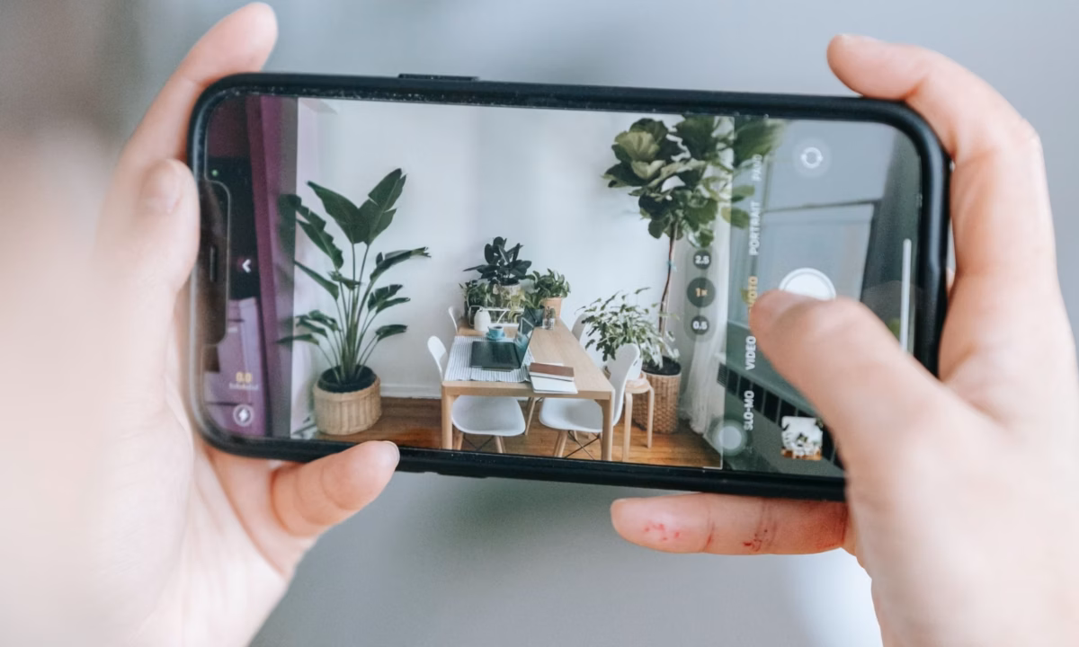 A realtor takes a photo of the interior of a house using a mobile phone.
