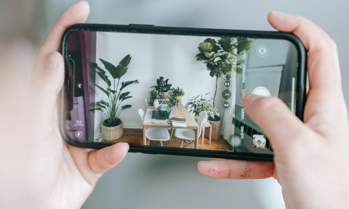 A realtor takes a photo of the interior of a house using a mobile phone.