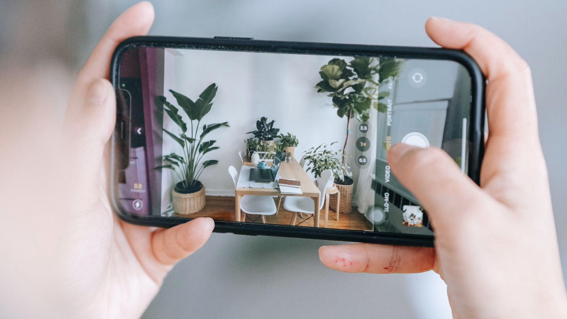 A realtor takes a photo of the interior of a house using a mobile phone.