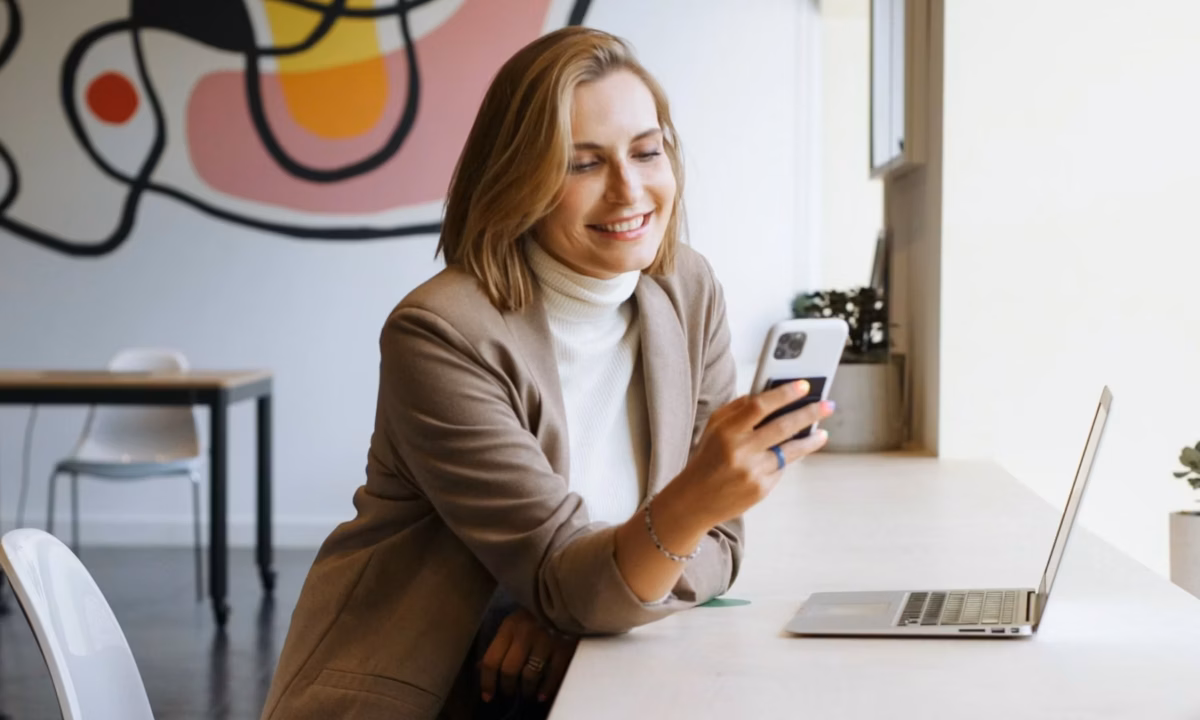 A cheerful realtor is learning how to use social media effectively for their marketing strategy from her phone.