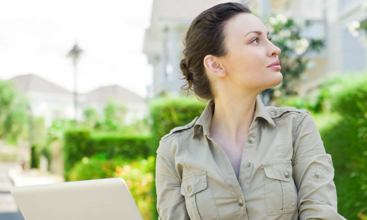 A realtor thinks about her social media presence online while looking away from her laptop.