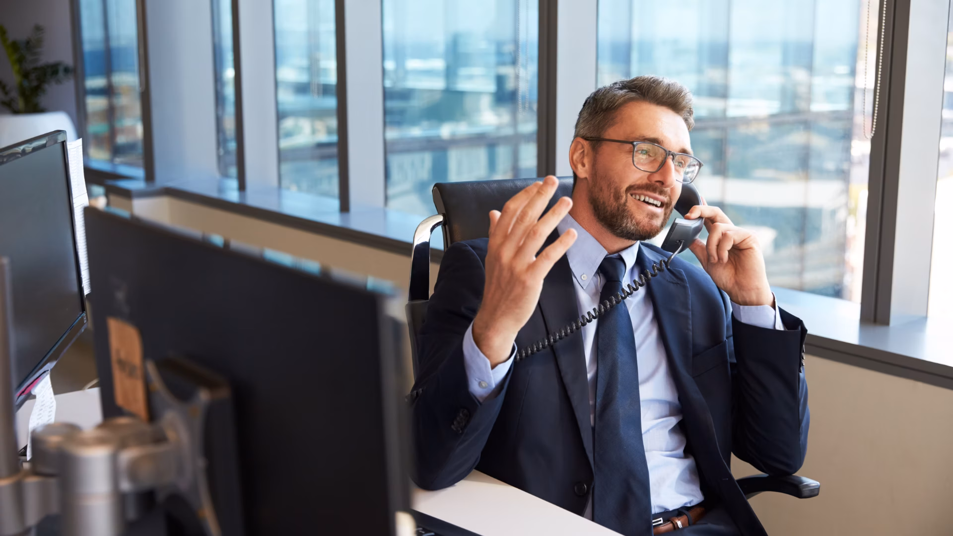 Man in suit sits at a desk on the phone explaining is unique selling proposition