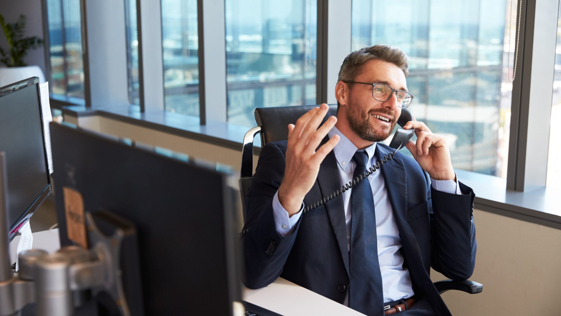 Man in suit sits at a desk on the phone explaining is unique selling proposition