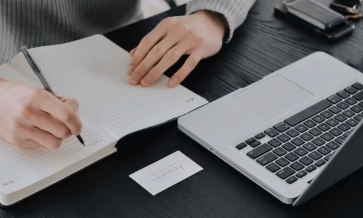 A real estate agent taking notes while in front of her laptop.