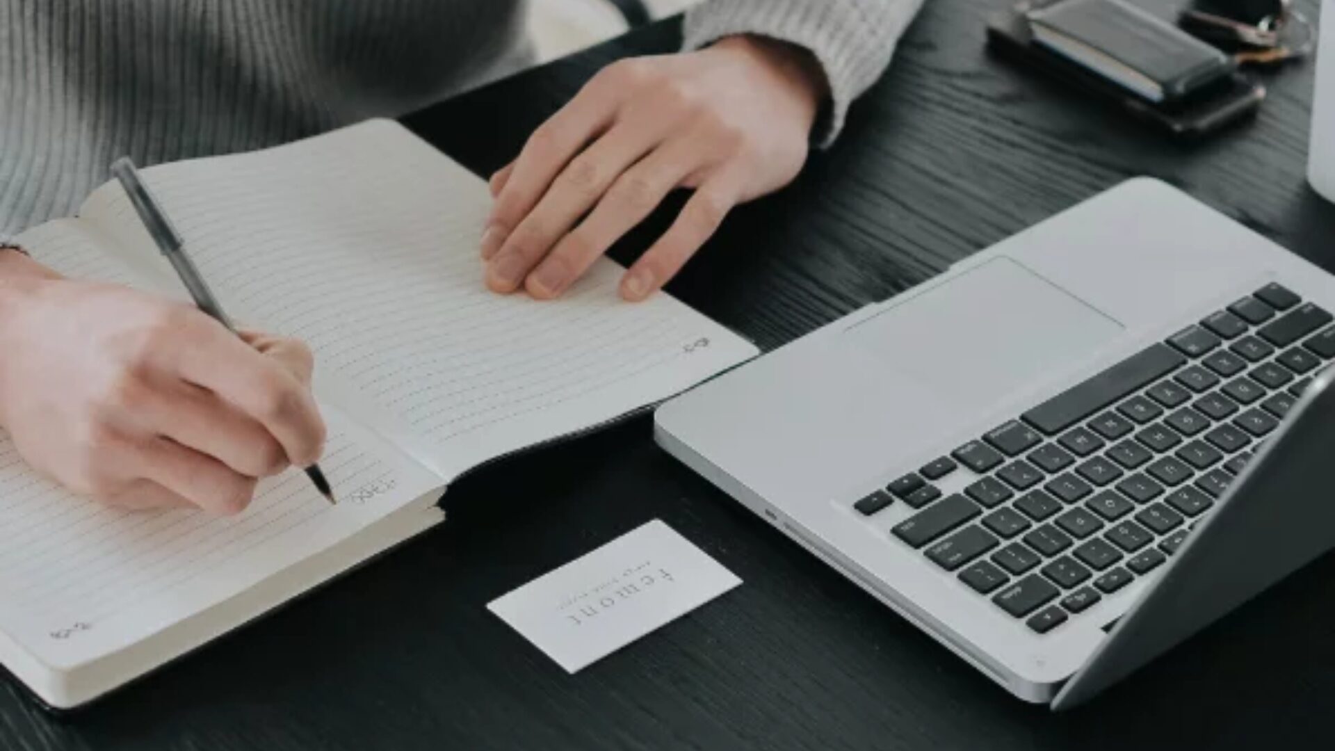 A real estate agent taking notes while in front of her laptop.