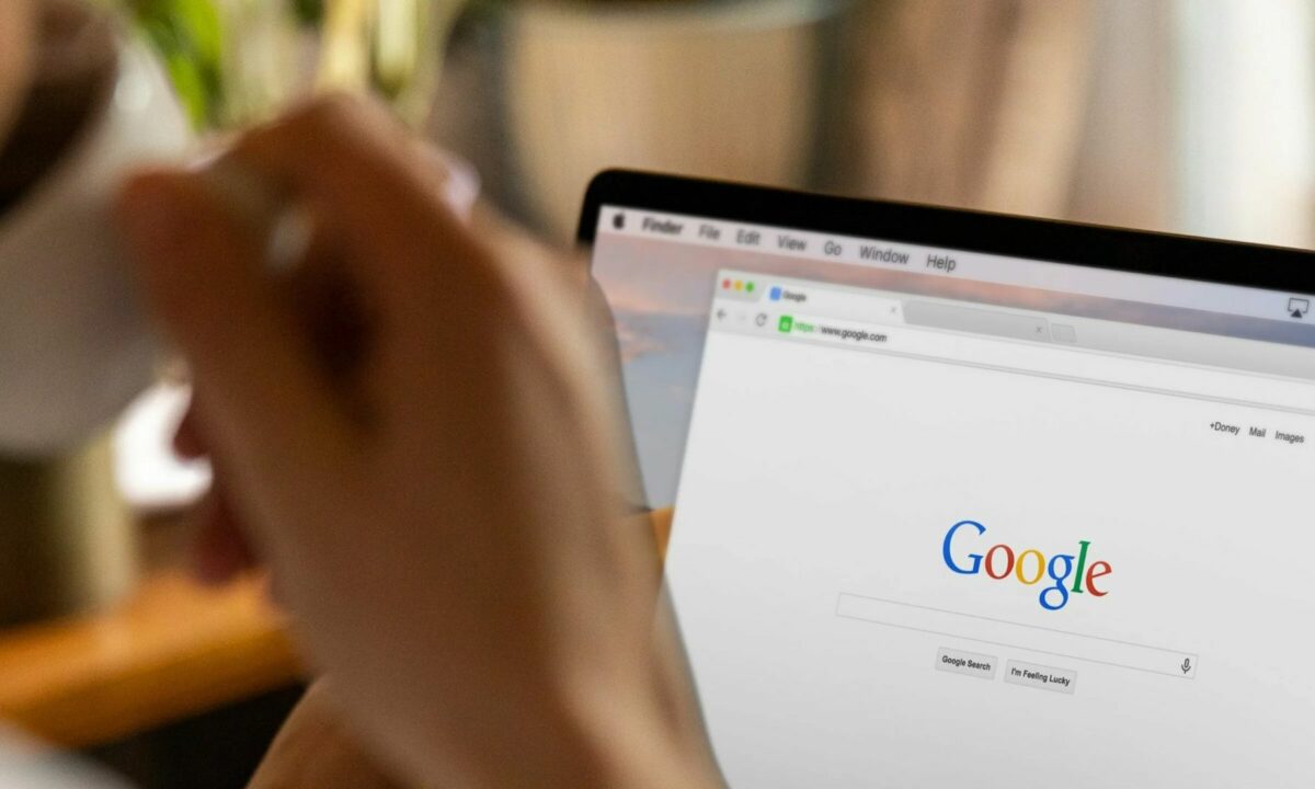 A real estate agent is sipping coffee in front of a laptop showing a Google search page.