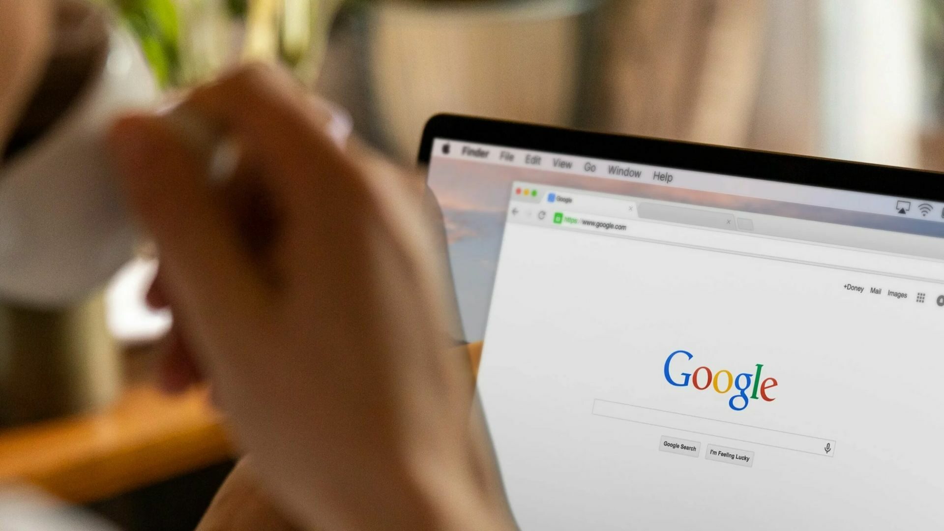 A real estate agent is sipping coffee in front of a laptop showing a Google search page.