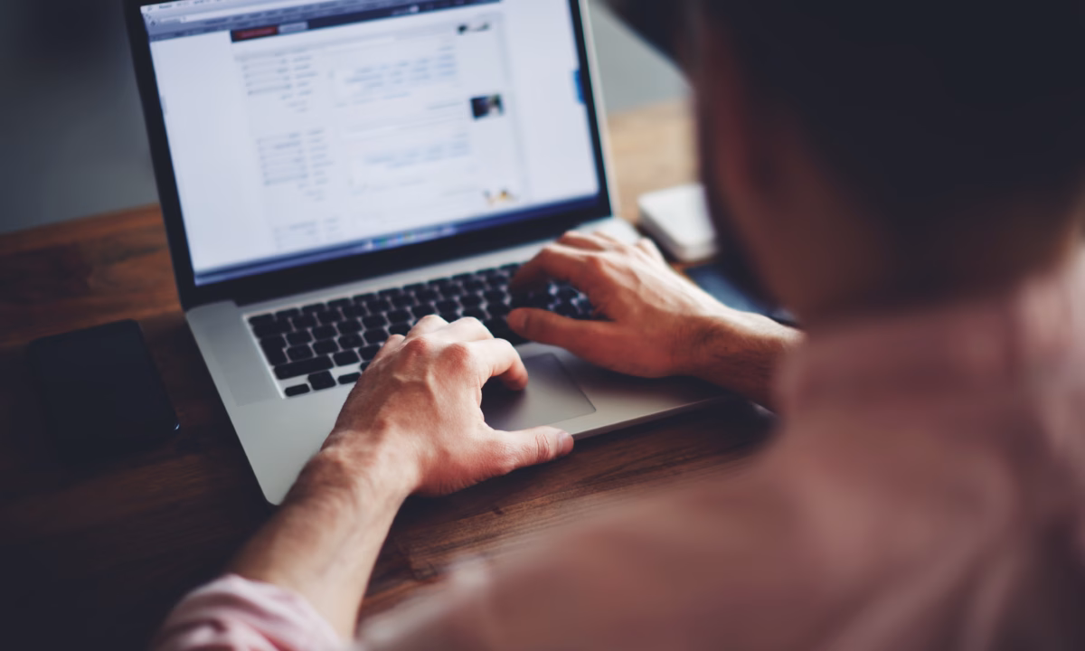 A man sits in front of a laptop, querying his database for real estate agents