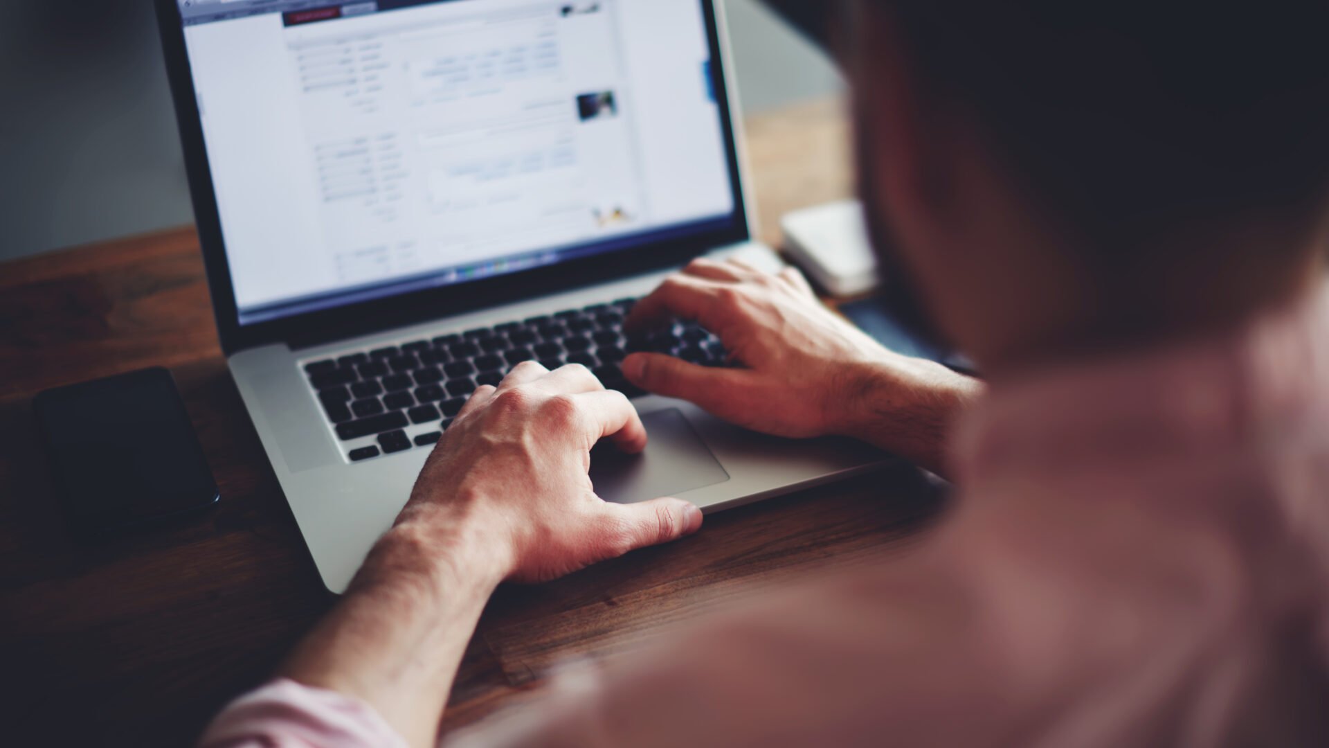 A man sits in front of a laptop, querying his database for real estate agents