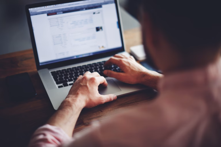 A man sits in front of a laptop, querying his database for real estate agents