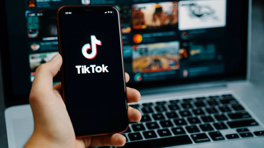 A real estate agent holds a mobile phone with a TikTok app logo.