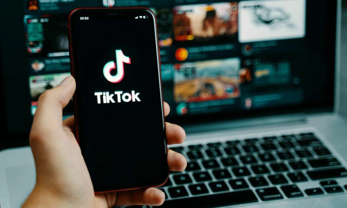 A real estate agent holds a mobile phone with a TikTok app logo.