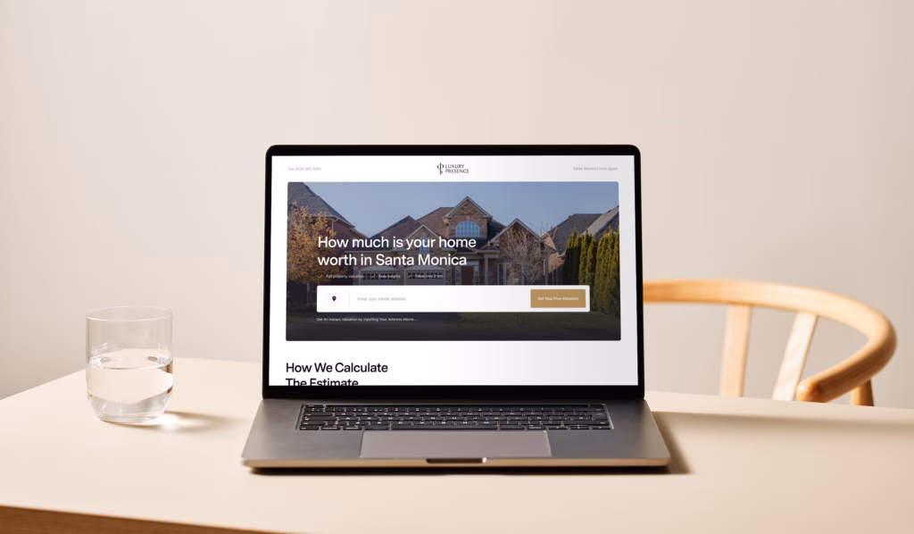 laptop sitting on table next to glass of water displaying a webpage about Real Estate Website User Interface (UI/UX)