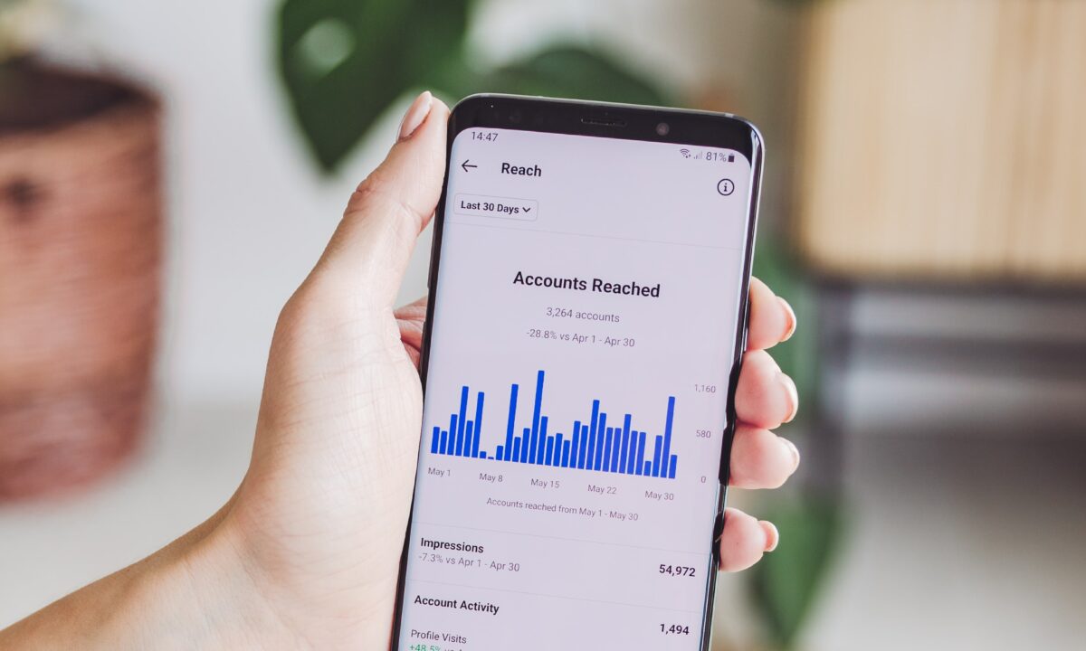 A realtor holds a mobile phone that shows the analytics of a social media page.