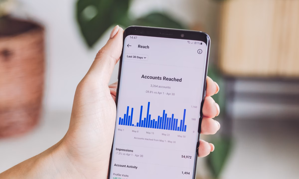 A realtor holds a mobile phone that shows the analytics of a social media page.