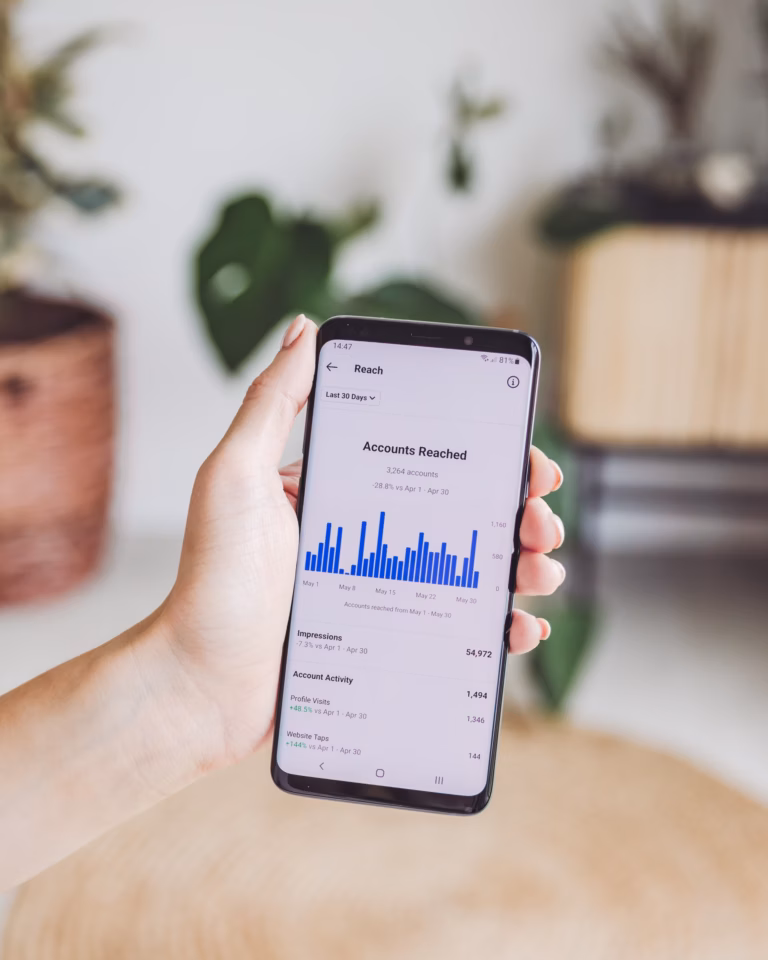 A realtor holds a mobile phone that shows the analytics of a social media page.