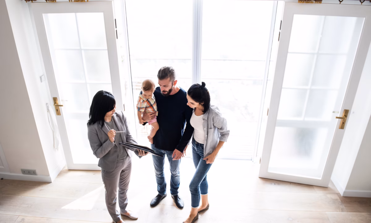 A realtor shows an open house sign-in sheet document from her tablet to a family that is touring the property.