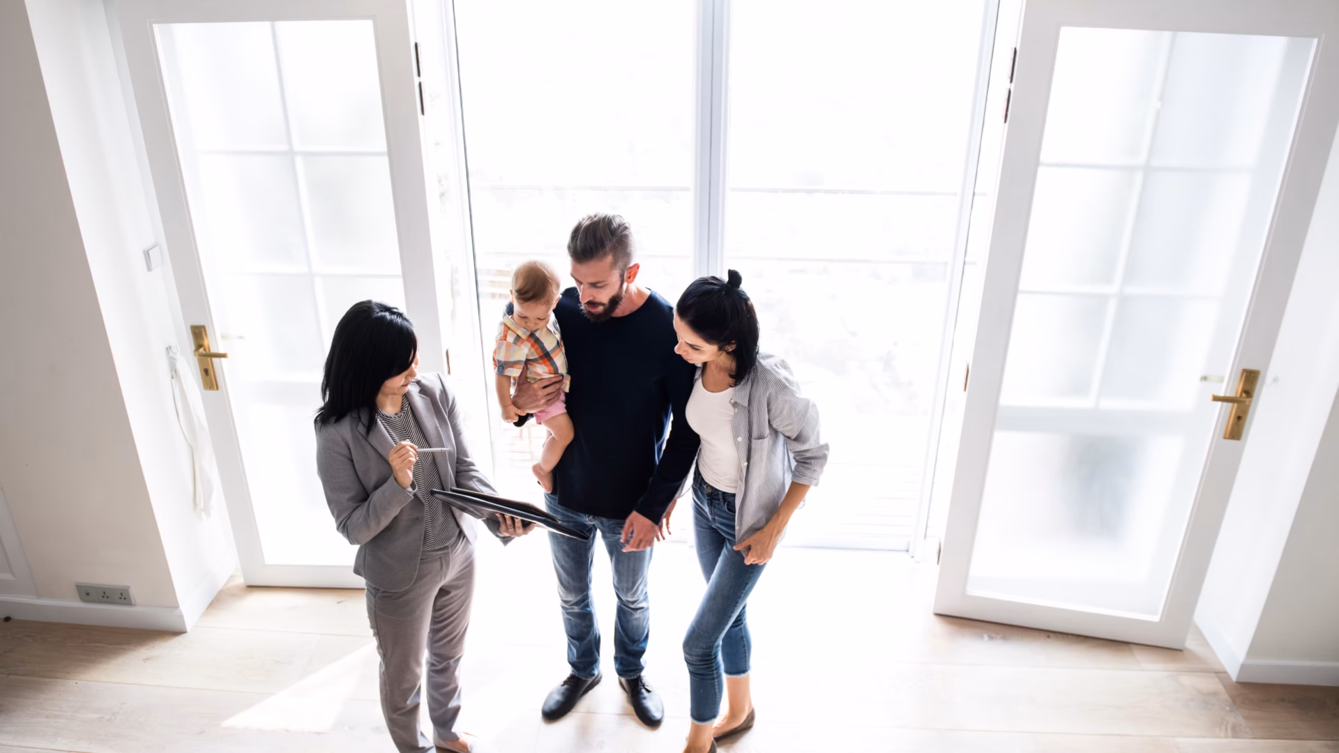 A realtor shows an open house sign-in sheet document from her tablet to a family that is touring the property.
