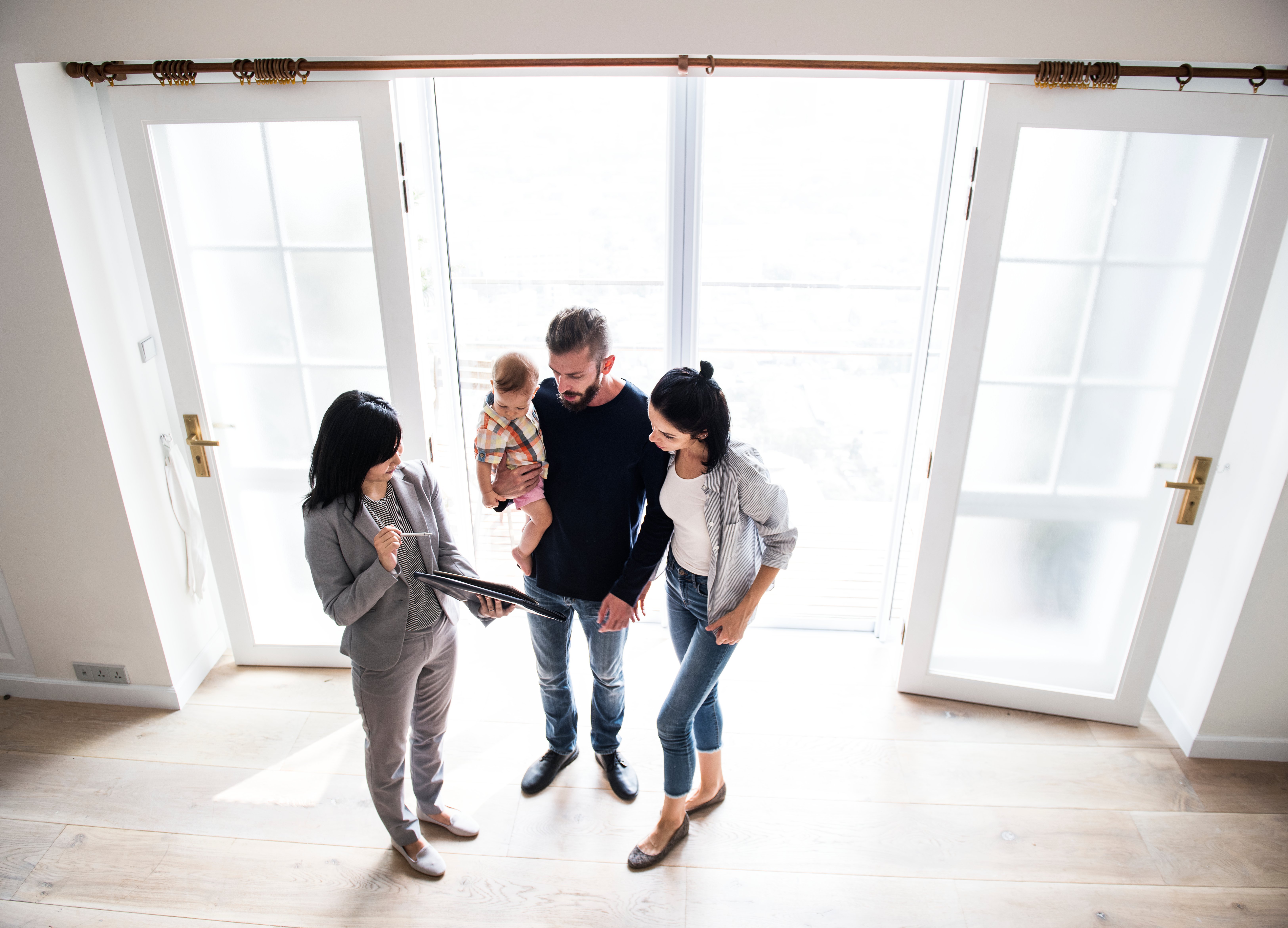 A realtor shows an open house sign-in sheet document from her tablet to a family that is touring the property.