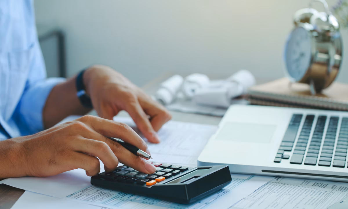 A real estate agent uses his calculator to work out real estate math formulas.