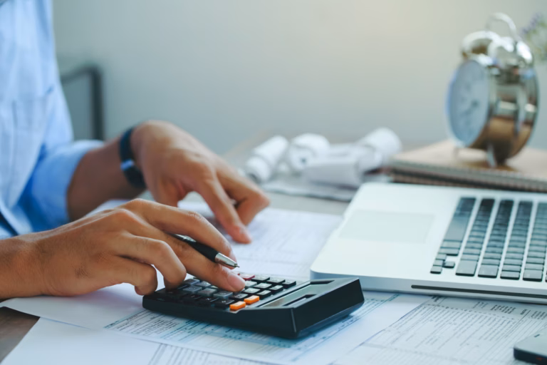 A real estate agent uses his calculator to work out real estate math formulas.