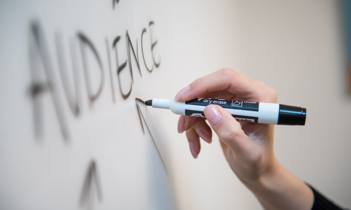 real estate agent writing the word "audience" on a white board trying to map out a marketing strategy to target the right audience at the right time