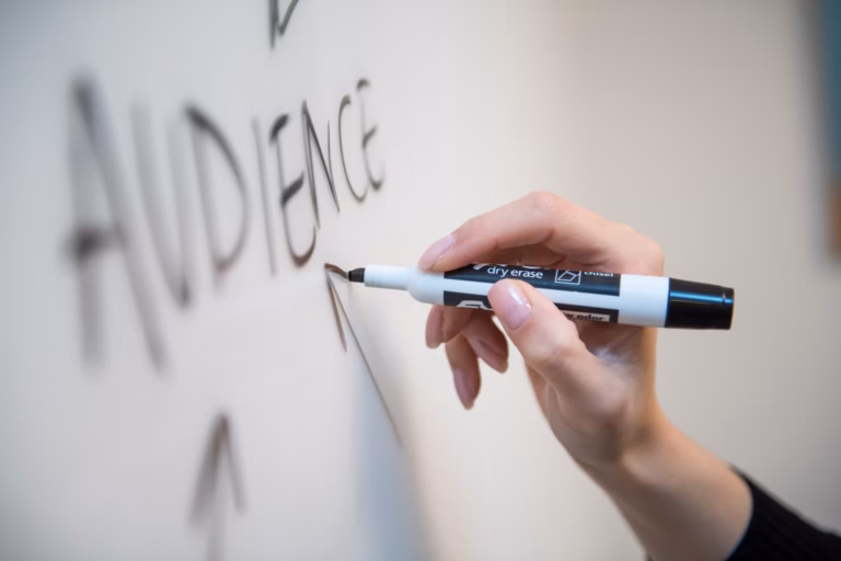 real estate agent writing the word "audience" on a white board trying to map out a marketing strategy to target the right audience at the right time