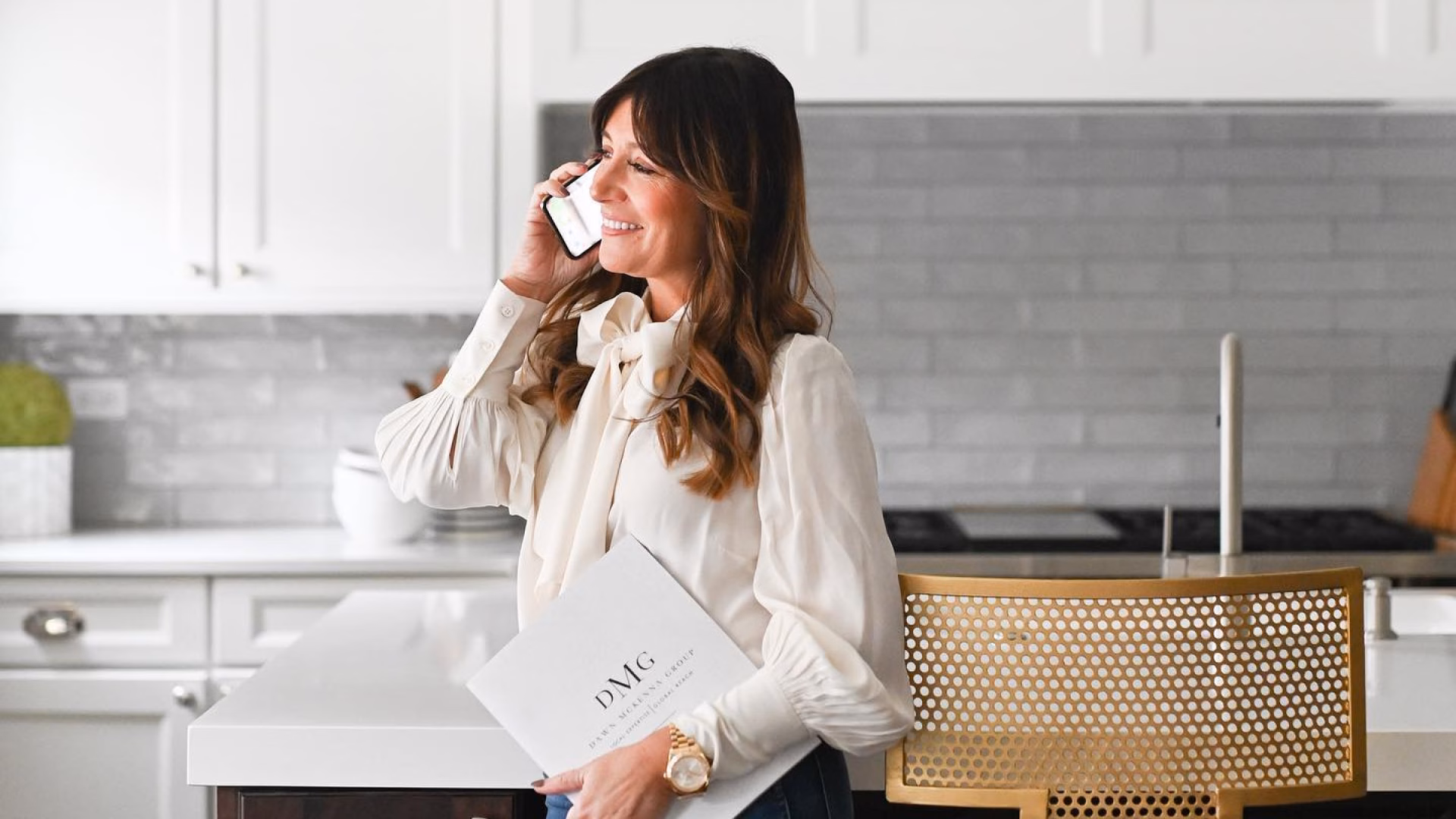 Image of real estate agent, Dawn Mckenna, standing in a kitchen and talking on iPhone