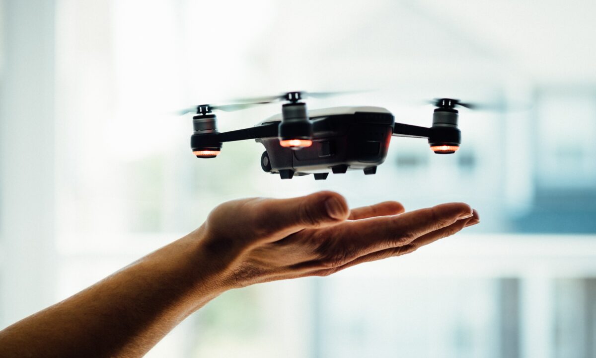 A real estate agent's hand utilizing a drone to capture aerial shots of a property for a listing video.