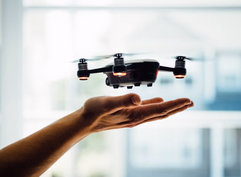 A real estate agent's hand utilizing a drone to capture aerial shots of a property for a listing video.