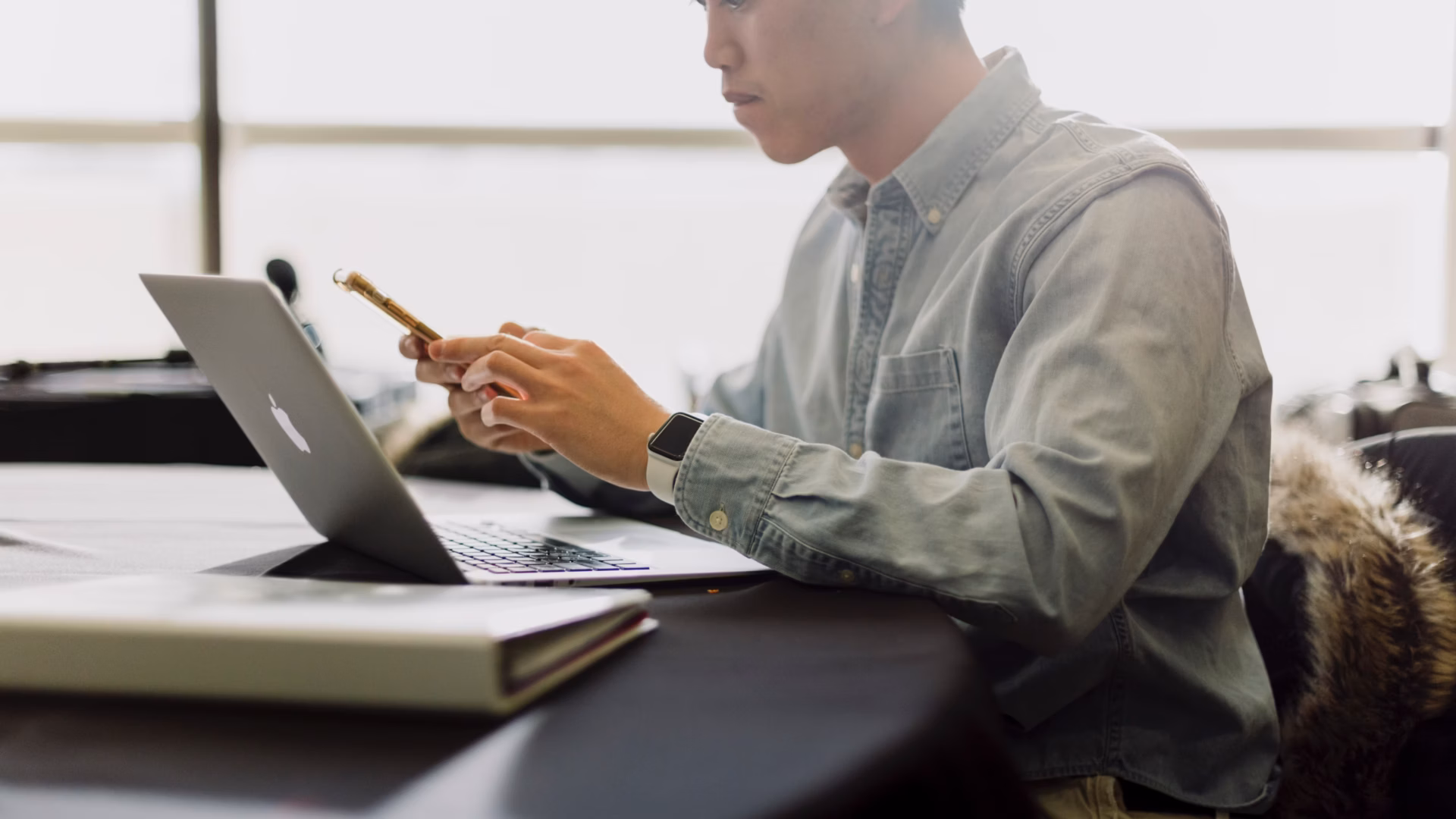 A real estate agent using a phone and a laptop, searches for pricing information about IDX website cost online.