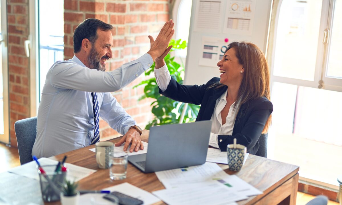 Two real estate agents high-fiving and successfully scaling their real estate network and driving new opportunities using solutions from Luxury Presence.