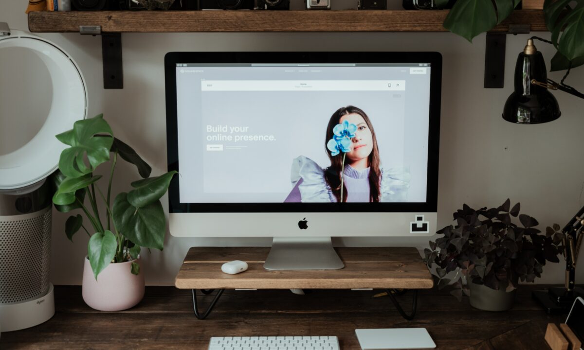 A Squarespace real estate website preview is displayed on a desktop computer atop a clean and minimalist workstation.