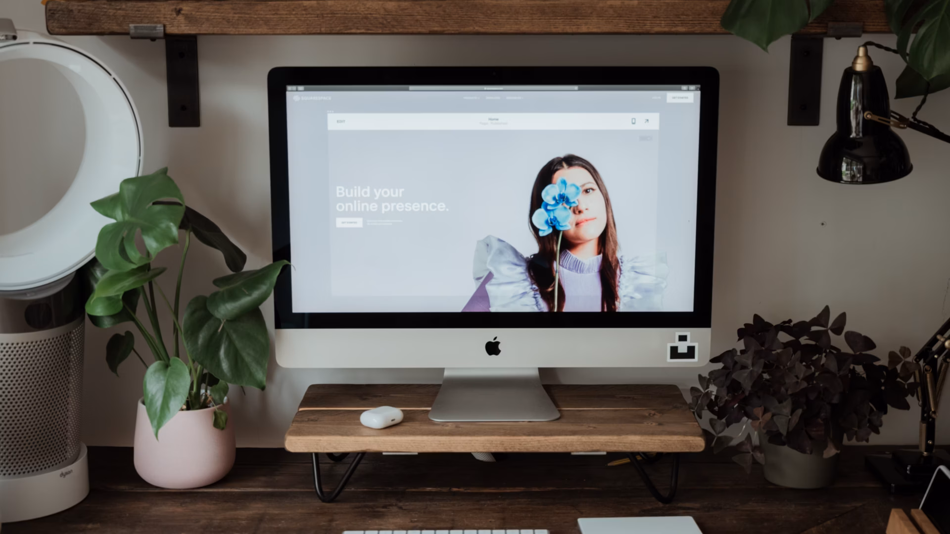 A Squarespace real estate website preview is displayed on a desktop computer atop a clean and minimalist workstation.