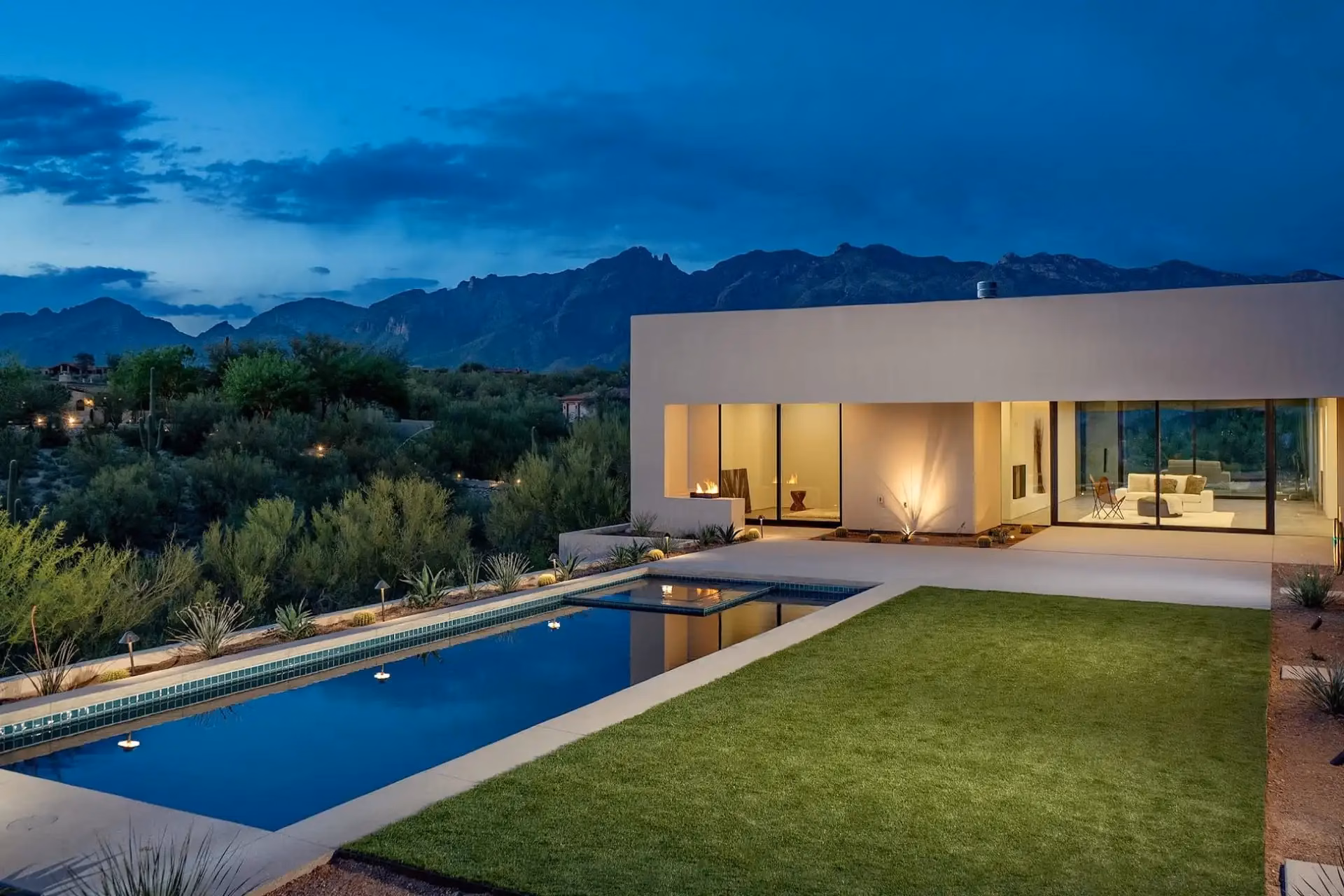One-story modern home with a pool overlooking mountains at dusk