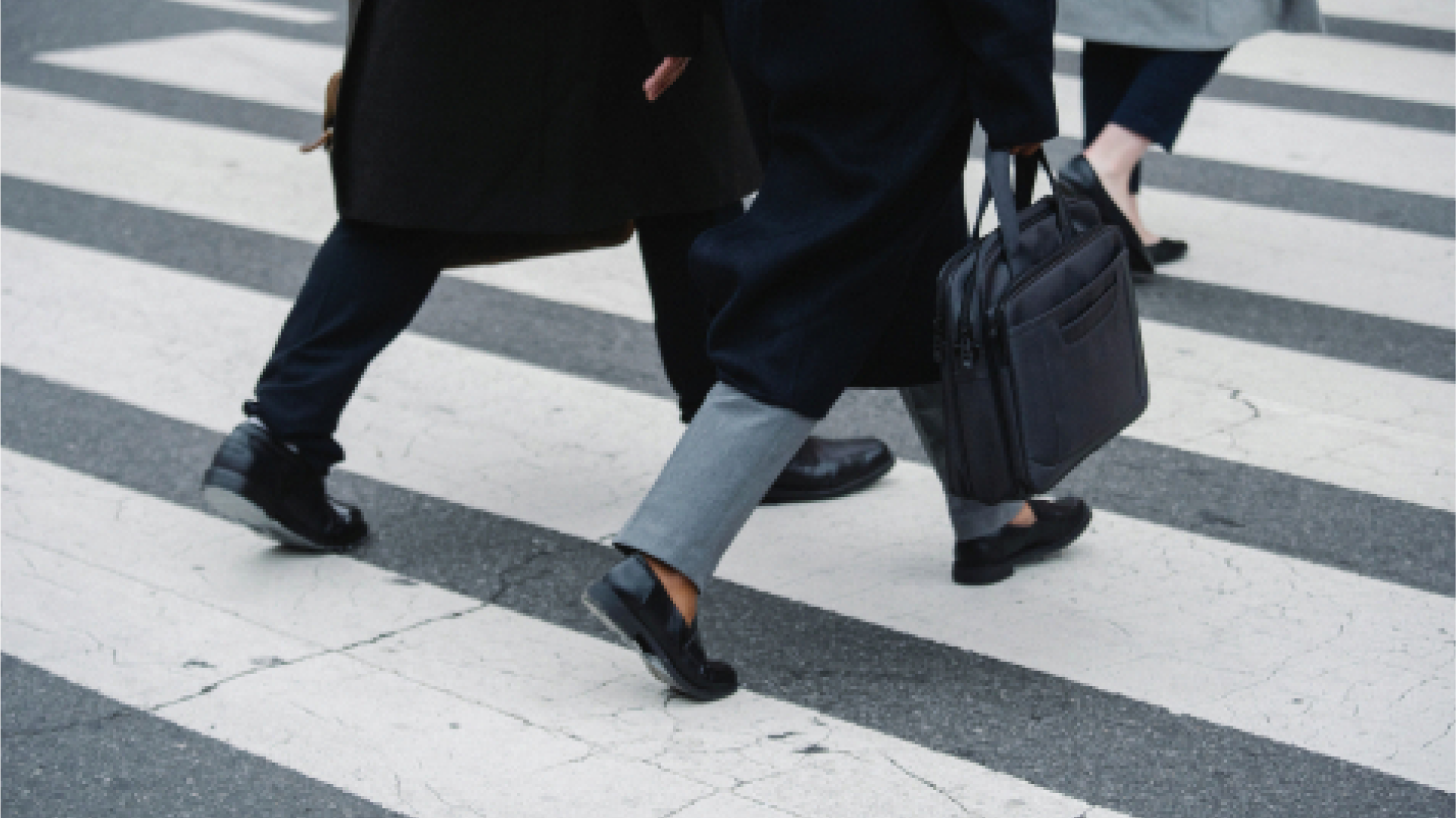 business professionals walking across crosswalk of street 