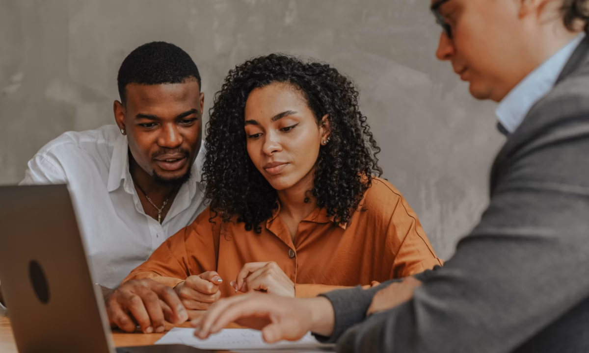 real estate agent on laptop consulting with first time homebuyers, a profitable real estate niche for this agent