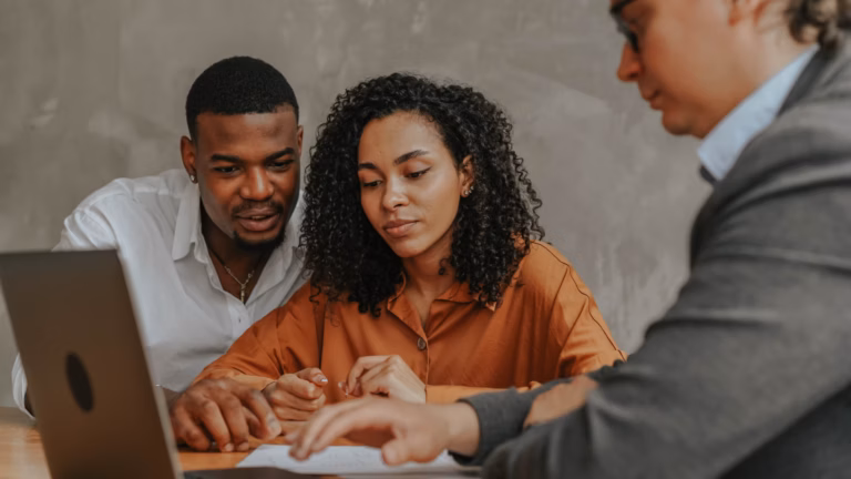 real estate agent on laptop consulting with first time homebuyers, a profitable real estate niche for this agent